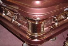 closeup of gold casket corner affixed to red coffin